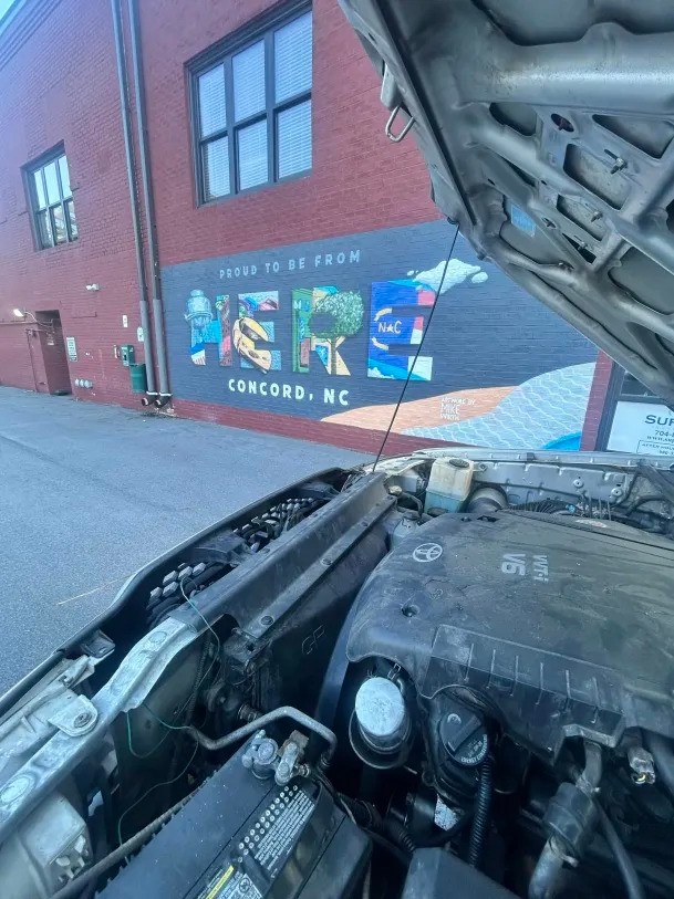 Mobile mechanic service in downtown Concord NC with hood open near local mural