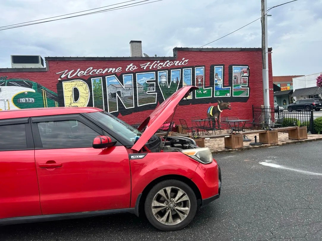 Mobile mechanic service in Pineville NC with hood open near historic Pineville mural